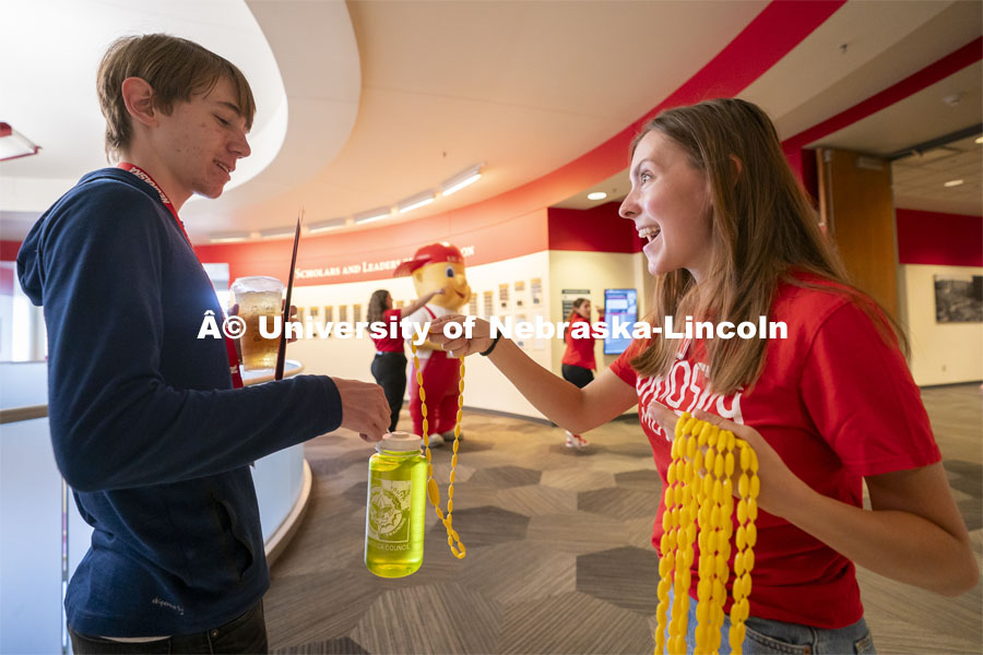 Campus host Morgan Tracy (right) hands Colin Leuthaeuser, of Omaha, Nebraska, a corn necklace during Red Letter Day inside the Nebraska Union. September 13, 2024. Photo by Jordan Opp for University Communication.